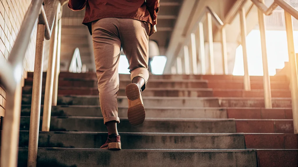 someone seen from behind going up some stairs to illustrate that each change we make takes up higher